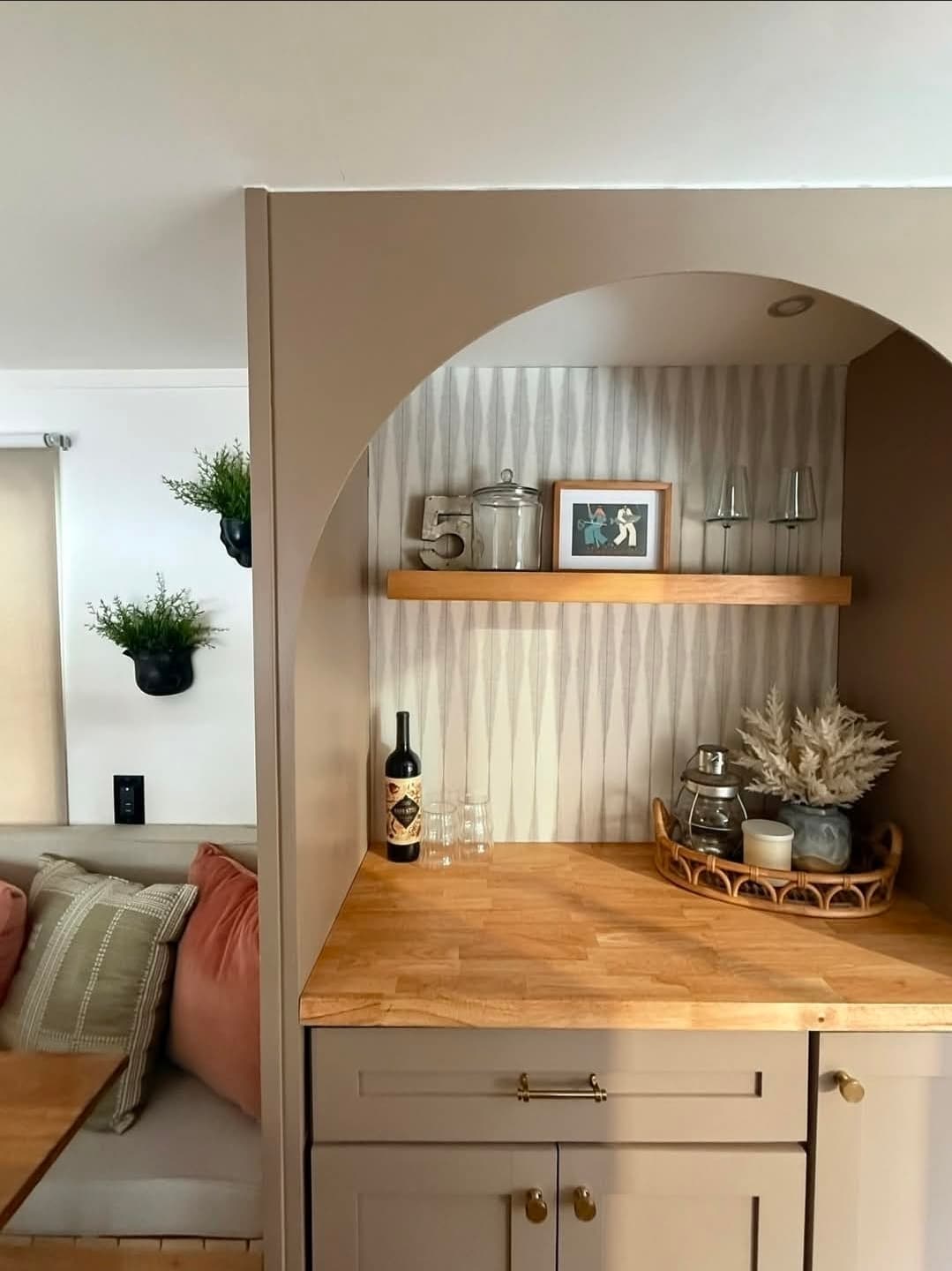 Val's renovated counter and beverage nook with open shelving, glassware, and a partial view of the living area.