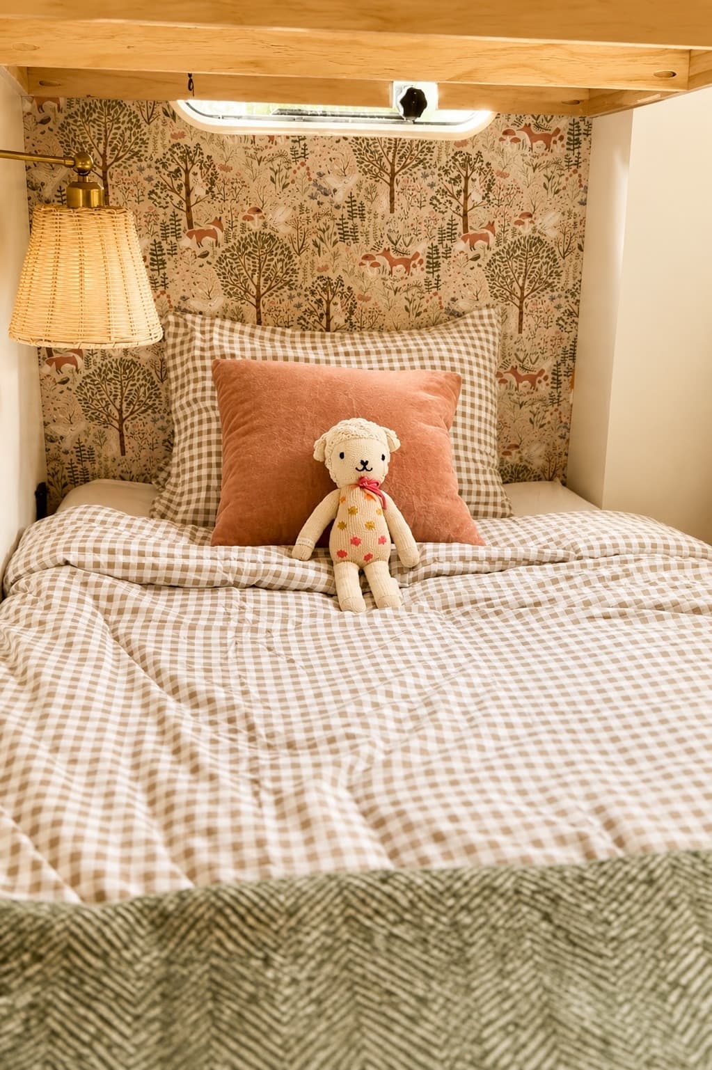 One of Val's twin bunk beds made up for a child, shown with a small lamb doll.